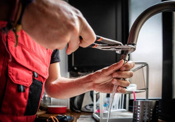 Plumber tightening copper P-trap under a Halifax kitchen sink