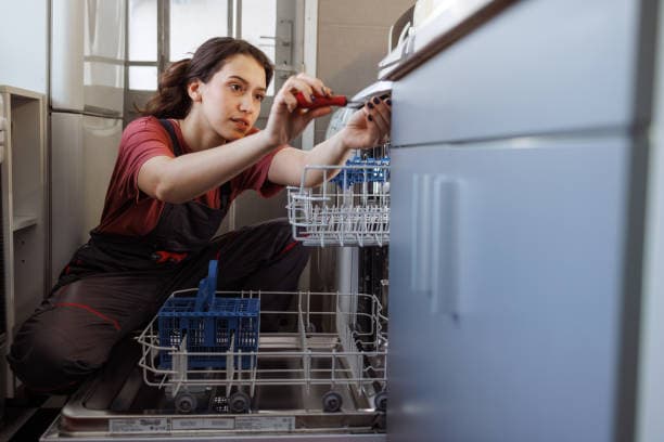 Appliance technician inspecting the rear of a refrigerator