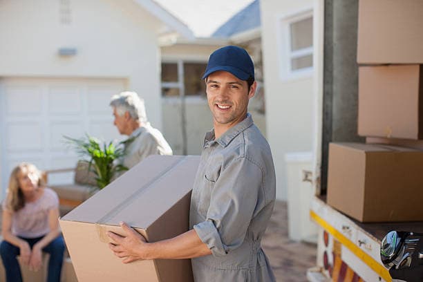 Two movers carrying boxes through the doorway